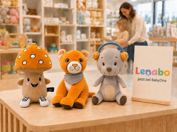Lenabies Aaron, Tali und Felix auf einer Verkaufsfläche im Spielwarenladen mit dem Hinweis „Lenabo jetzt bei BabyOne“