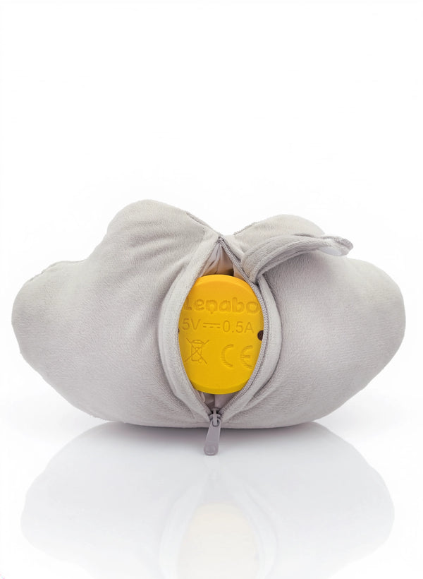 Das Plüschtier Lina aus der Lenabo Inselwelt ist von hinten zu sehen. Die graue, wolkenförmige Hülle ist über einen mittigen Reißverschluss geöffnet. Darin ist der gelbe Lenabo Smart Speaker sichtbar, auf dem technische Angaben wie ‚5V — 0.5A‘ und Symbole stehen.