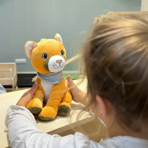 Lenabo Starter Kit unter anderem mit Lenabie Tali (Puma) und Lenabo Smart Speaker. Kind sitzt gespannt mit flauschigem Audio-Kuscheltier am Tisch und lauscht; interaktives Hörspiel-Kuscheltier mit herausnehmbarem, mobilem Smart Speaker für über 60 Minuten Spielzeit, Geschichten, Hörspiele und Lerninhalte für Kinder von 0–7 Jahren.