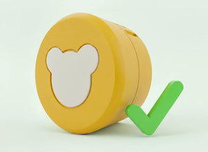 Der gelbe Lenabo Smart Speaker mit weißem Bären-Icon auf der Vorderseite liegt leicht seitlich vor hellem Hintergrund. Rechts daneben steht ein großes grünes Häkchen, das den Lautsprecher als korrekt oder kompatibel markiert.