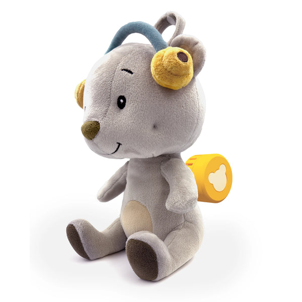 Auf dem Bild sitzt das Plüschtier Aaron, ein grauer Bär mit blauen Ohrwärmern und gelben Plüsch-Ohren. Das gelbe runde Soundmodul ist seitlich am Rücken sichtbar. Der Bär hat ein freundliches Gesicht und sitzt auf einem weißen Hintergrund.