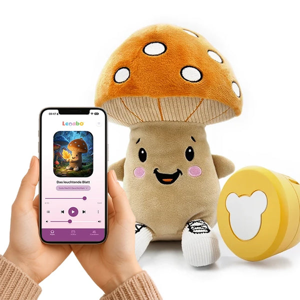 Der Lenabo Charakter Felix, ein beigefarbener Pilz mit großem braunen Hut und weißen Punkten, sitzt aufrecht. Links hält eine Person ein Smartphone mit der geöffneten Lenabo App, die das Hörspiel ‚Das leuchtende Blatt‘ zeigt. Rechts daneben liegt der gelbe Lenabo Smart Speaker.