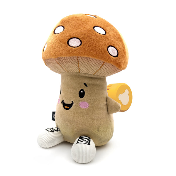 Der Lenabo Charakter Felix sitzt aufrecht. Er hat einen großen braunen Pilzhut mit weißen Punkten, einen beigefarbenen Körper, ein fröhliches Gesicht mit rosa Wangen und weiße Stofffüße mit schwarzen Schnürsenkel-Stickereien. Auf seiner Rückseite ist der gelbe Lenabo Smart Speaker sichtbar.